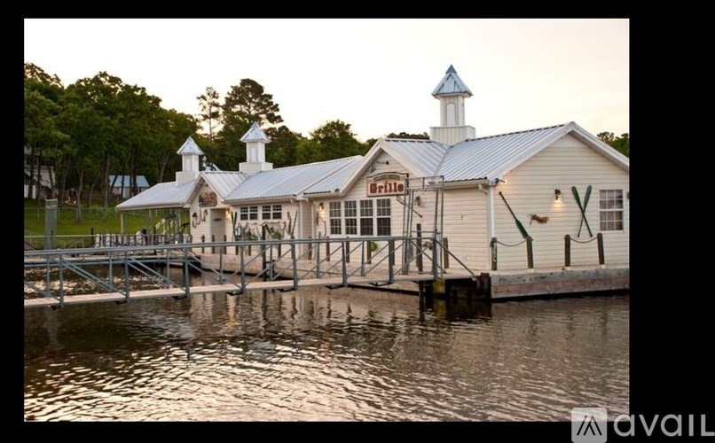 A building with a blue roof and a white steeple is situated on the water.