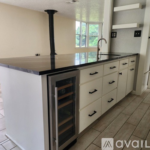 A kitchen with a black countertop and white cabinets.