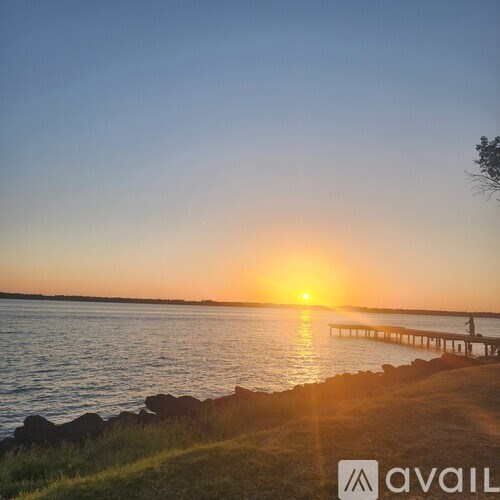 A sunset over a body of water with a dock in the distance.
