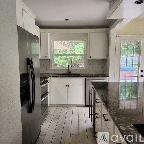 A kitchen with white cabinets and a black fridge.