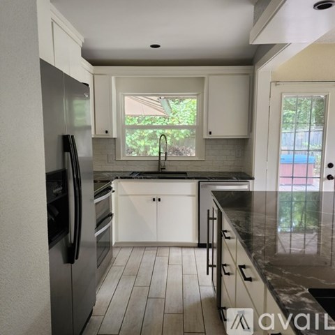 A kitchen with white cabinets and a black fridge.
