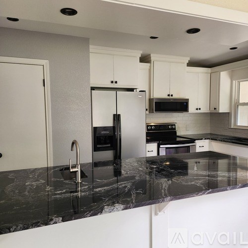 A kitchen with a marble countertop and stainless steel appliances.