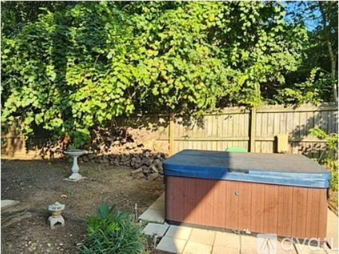 A hot tub sits in a backyard surrounded by greenery.