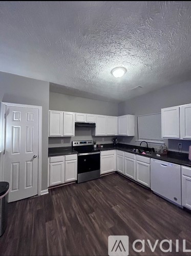 A kitchen with white cabinets and a wooden floor.