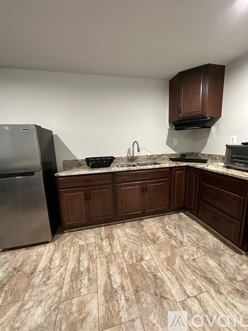 A kitchen with brown cabinets and a marble countertop.