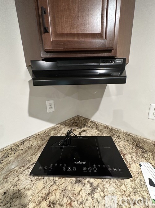A black induction cooktop is on a granite countertop.