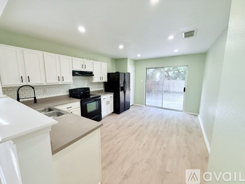 A kitchen with black appliances and white cabinets.