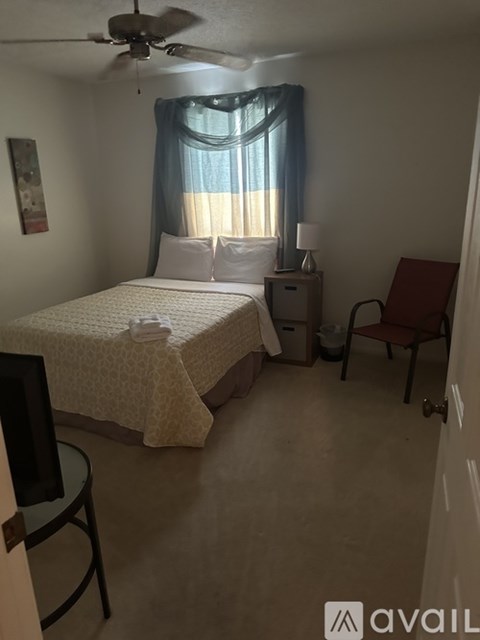 A bedroom with a bed, chair, and window.