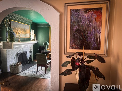 A room with a fireplace and a painting of purple flowers.