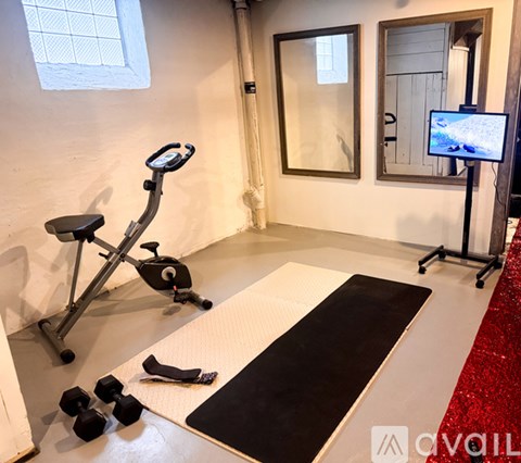 A home gym with a stationary bike, a yoga mat, and dumbbells.
