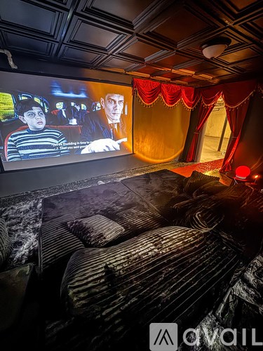 A movie theater with a large screen and a row of seats.