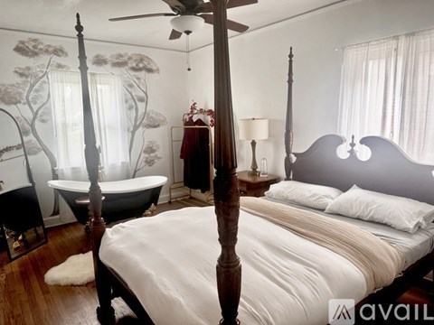 A bedroom with a large bed and a bathtub.