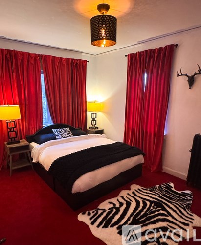 A bedroom with red carpet and a zebra rug.