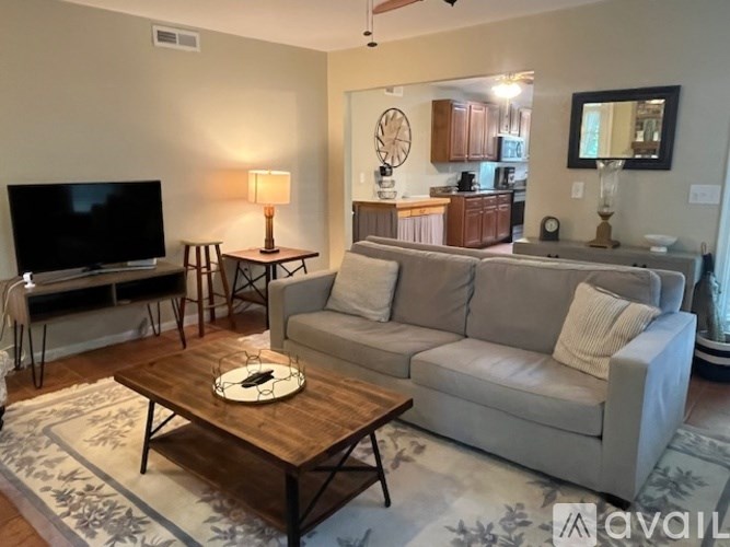 A living room with a grey couch, a wooden coffee table, and a flat screen TV.