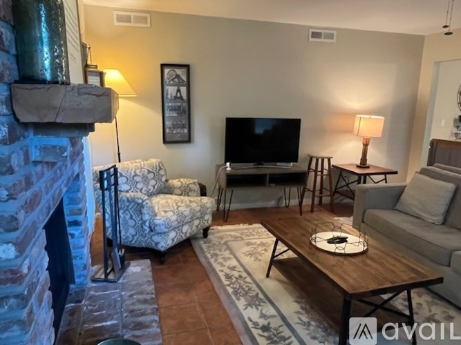 A living room with a stone fireplace and a grey couch.