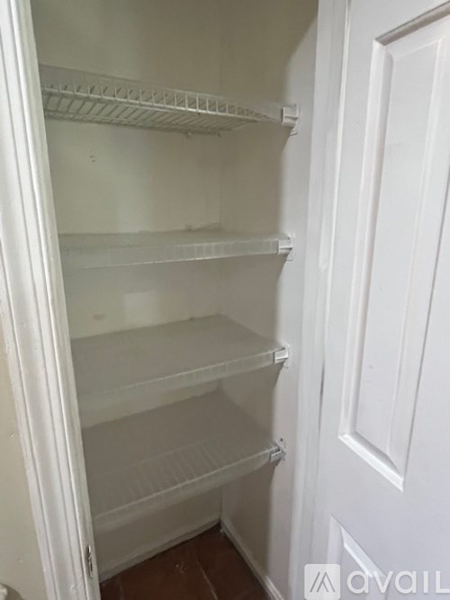 Empty white shelves in a white refrigerator.