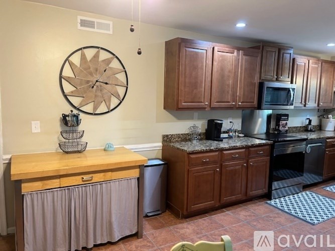 A kitchen with wooden cabinets and a large clock on the wall.