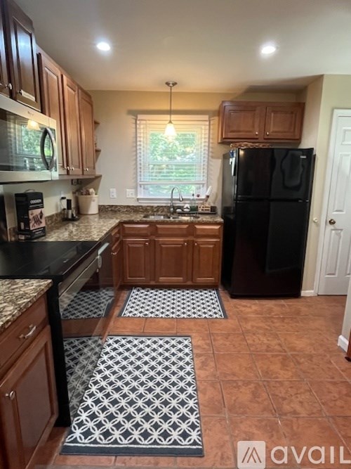 A kitchen with black appliances and wooden cabinets.