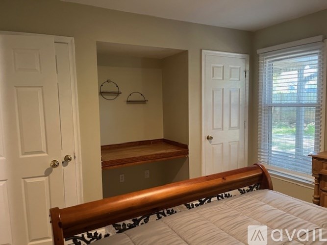 A bedroom with a bed, a window with blinds, and a wooden bench.