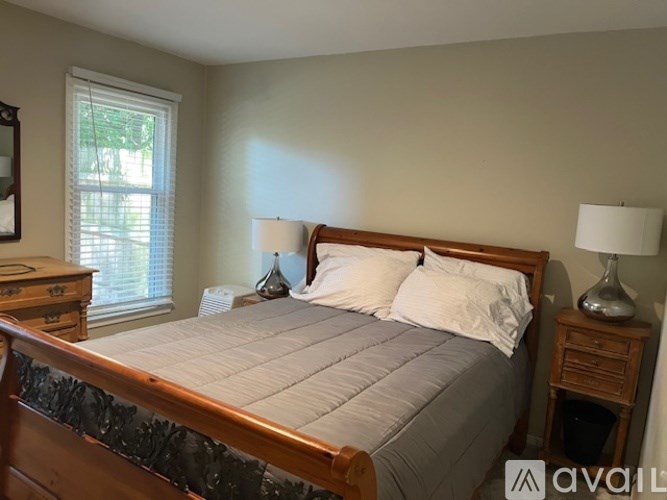 A bedroom with a bed, nightstand, and window.