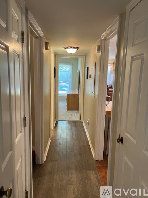 A long hallway with white doors and a light at the end.