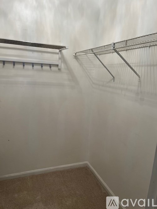 Empty room with a carpeted floor and a metal rack on the wall.