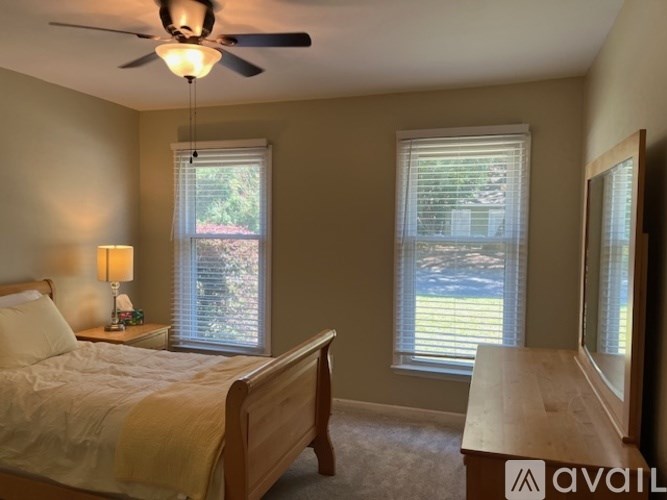 A bedroom with a bed, a ceiling fan, and a window with blinds.