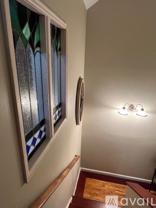 A hallway with a wooden floor and a wall-mounted light fixture.