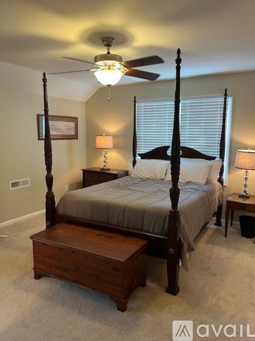 A bedroom with a four poster bed and a ceiling fan.