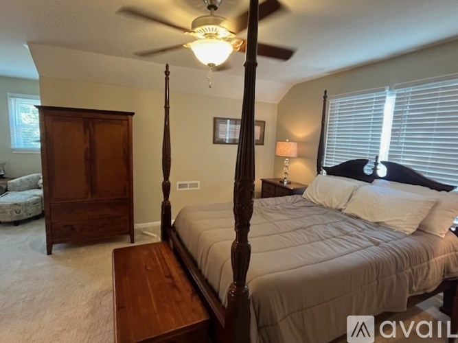 A bedroom with a four poster bed and a wooden dresser.