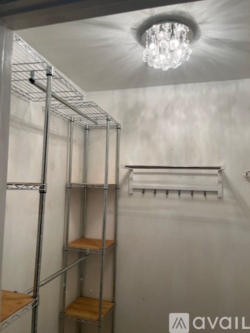 A room with a chandelier, shelving unit, and a white wall.