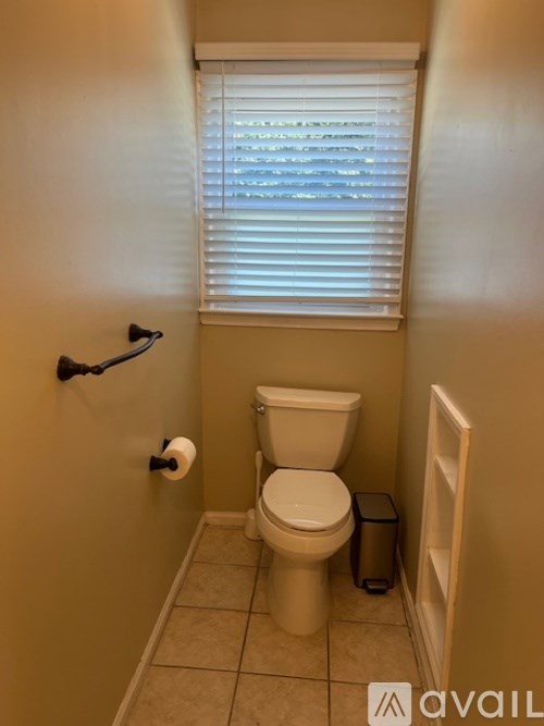 A small bathroom with a toilet and a window with blinds.