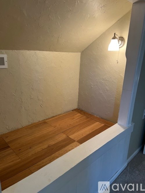 A room with a wooden floor and a white wall.