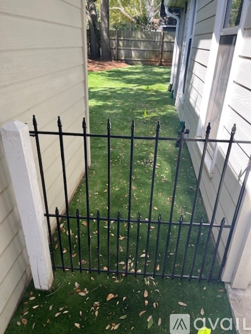 A black metal fence is in front of a white house.