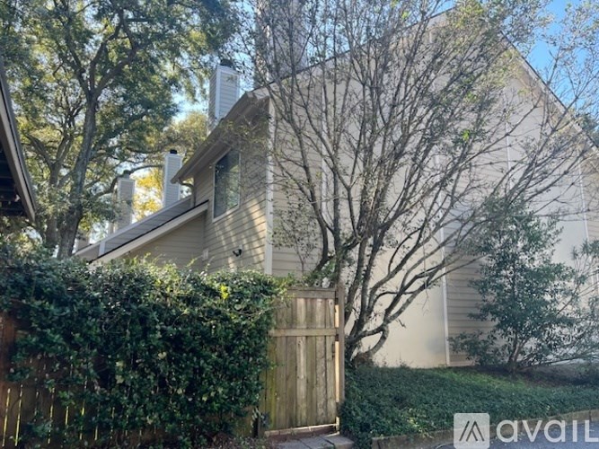 A house with a fence and a tree in front of it.