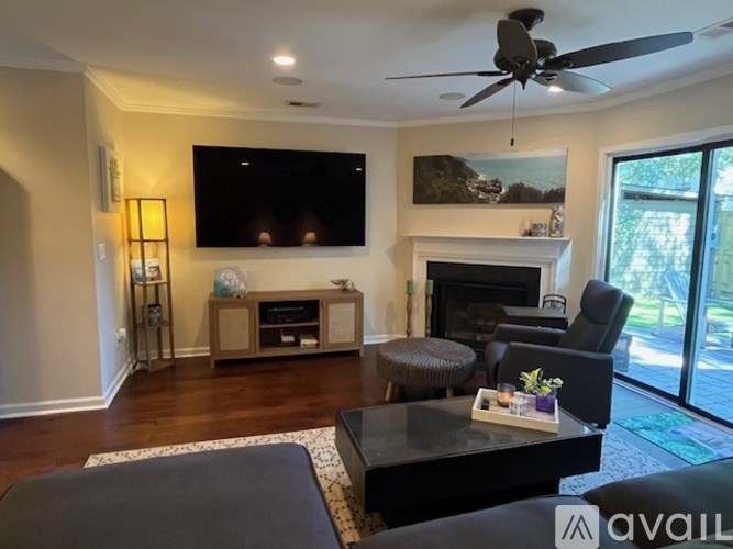 A living room with a fireplace, a television, and a ceiling fan.