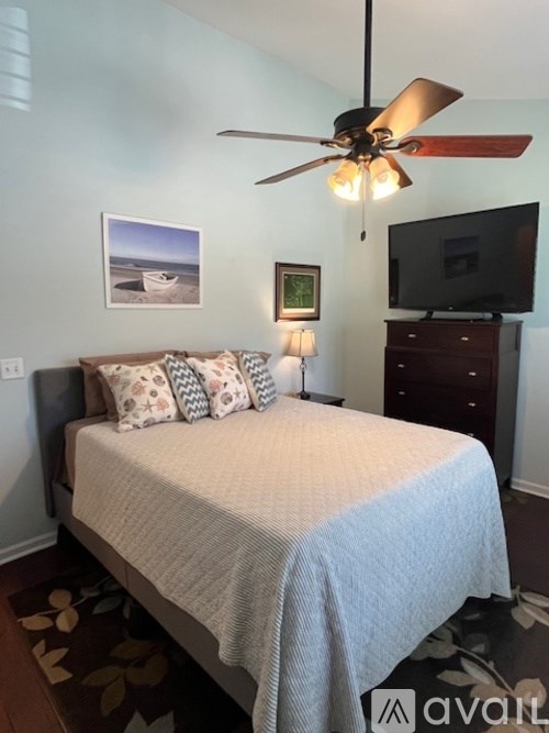 A bedroom with a bed, a ceiling fan, and a television.