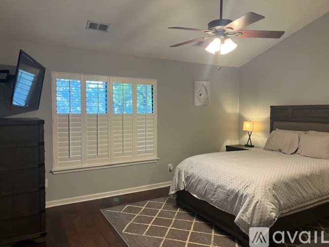 A bedroom with a bed, dresser, and window with blinds.
