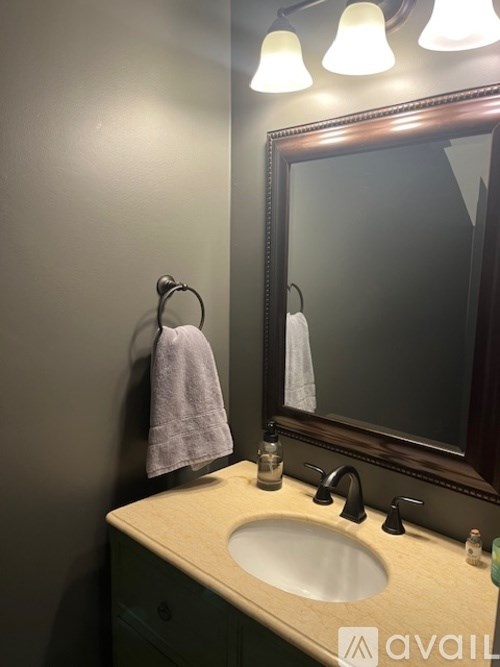 A bathroom with a sink, mirror, and light fixture.