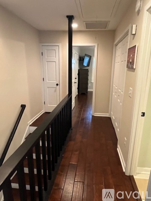 A hallway with a wooden floor and a black railing.