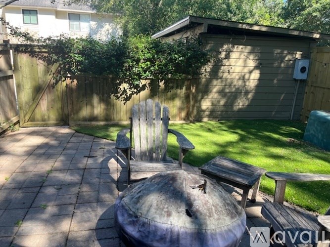 A backyard with a wooden chair and a large pot.