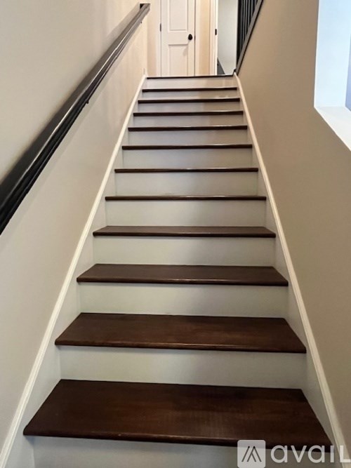 A staircase with wooden steps and a black handrail.