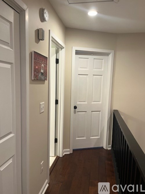 A hallway with a white door and a white wall.