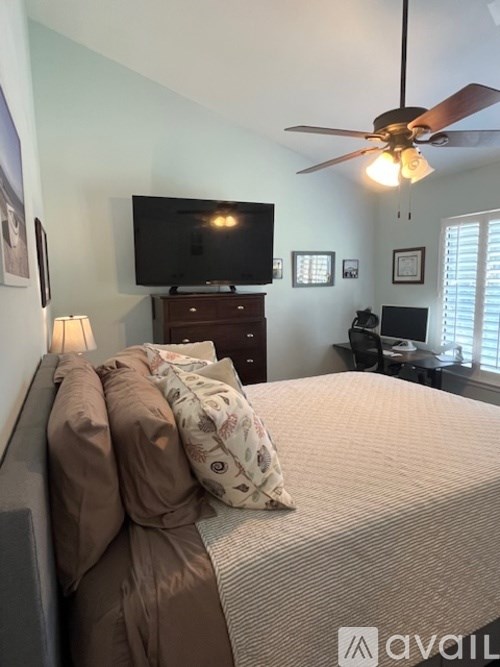 A bedroom with a bed, a ceiling fan, and a television.