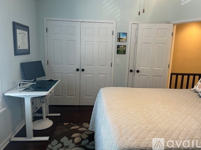 A bedroom with a bed, desk, and three doors.