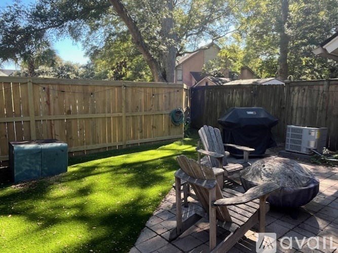 A backyard with a wooden fence, a small table and chairs, and a grill.