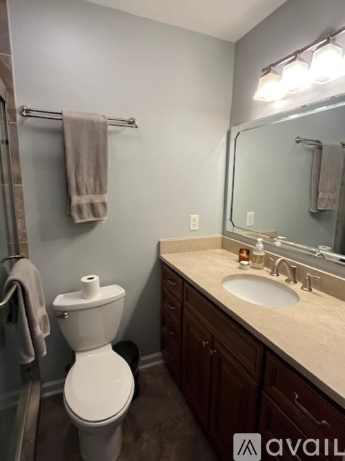 A bathroom with a toilet, sink, mirror, and towel rack.