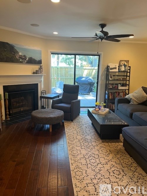 A living room with a fireplace and a ceiling fan.