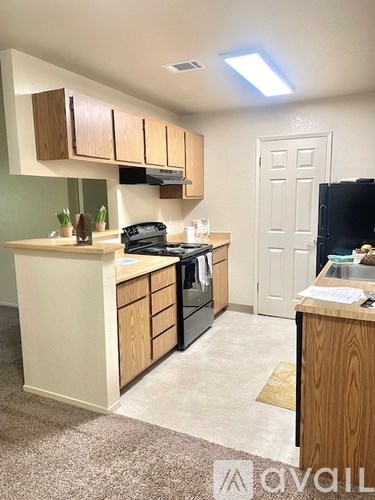 A kitchen with wooden cabinets and a black fridge.