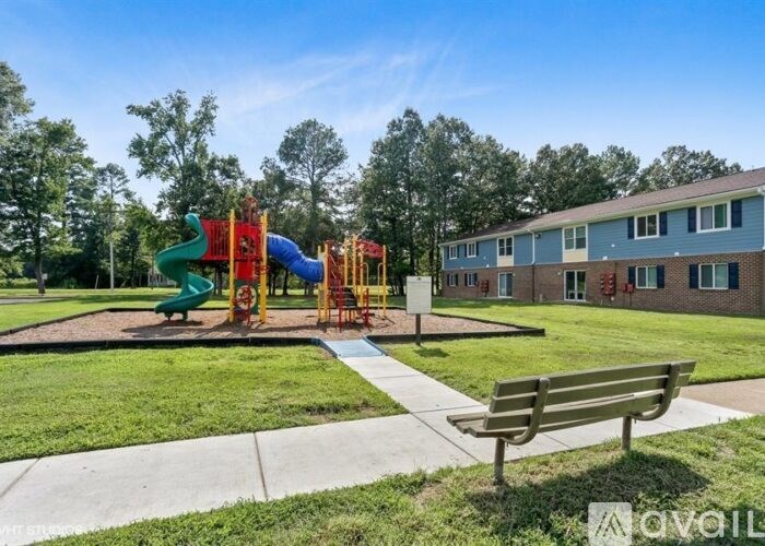 A playground with a slide and a bench in front of a building.